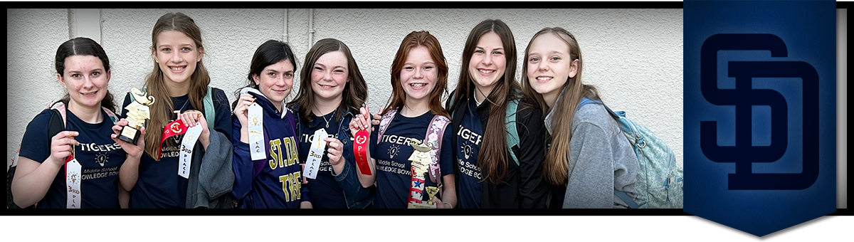 Group of girls smiling and holding up ribbons